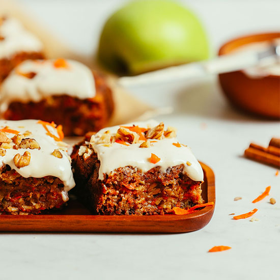 Slices of Carrot Apple Snack Cake on a platter and parchment paper