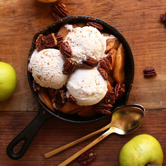 Mini cast-iron skillet filled with cooked apples, ice cream, and pecans