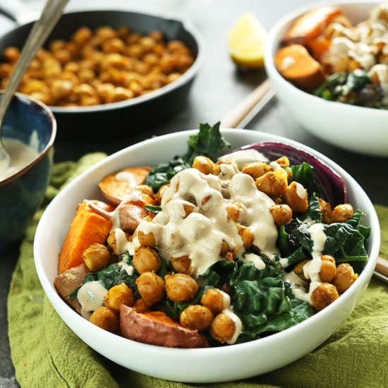 Healthy Sweet Potato Chickpea Buddha Bowls beside a bowl of tahini sauce and skillet of chickpeas