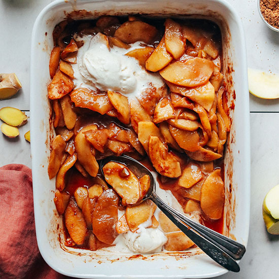 Spoons in a pan of Cinnamon Baked Apples topped with vegan ice cream
