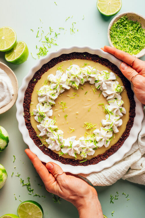 Hands holding the sides of a pie plate of vegan gluten-free key lime pie