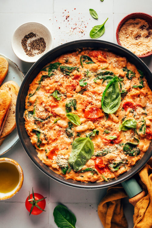 Skillet of Italian white beans with burst tomatoes, spinach, basil, and cashew cream