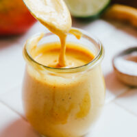 Spoonful of mango vinaigrette salad dressing dripping into a jar