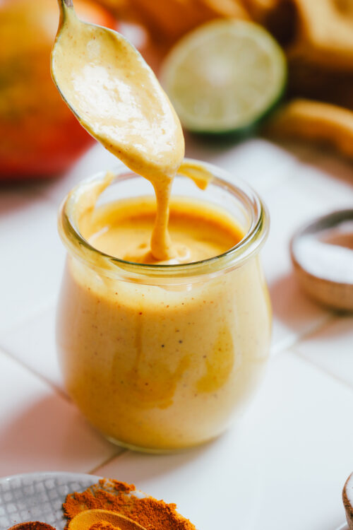 Spoonful of mango vinaigrette salad dressing dripping into a jar
