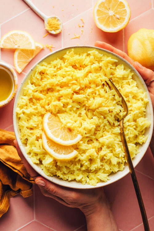 Hands holding a bowl of our easy vegan Greek-inspired lemon rice