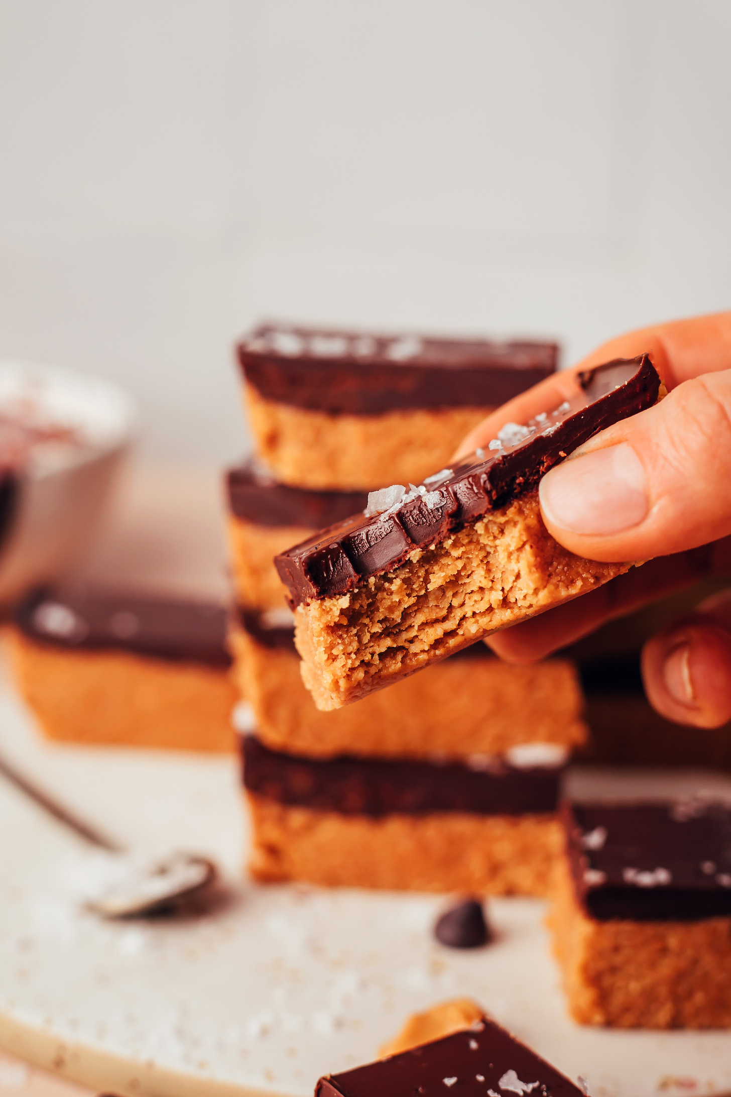 Holding a no-bake chocolate peanut butter cup bar topped with flaky salt