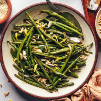Overhead shot of a bowl of roasted green beans with slivered almonds and lemon zest