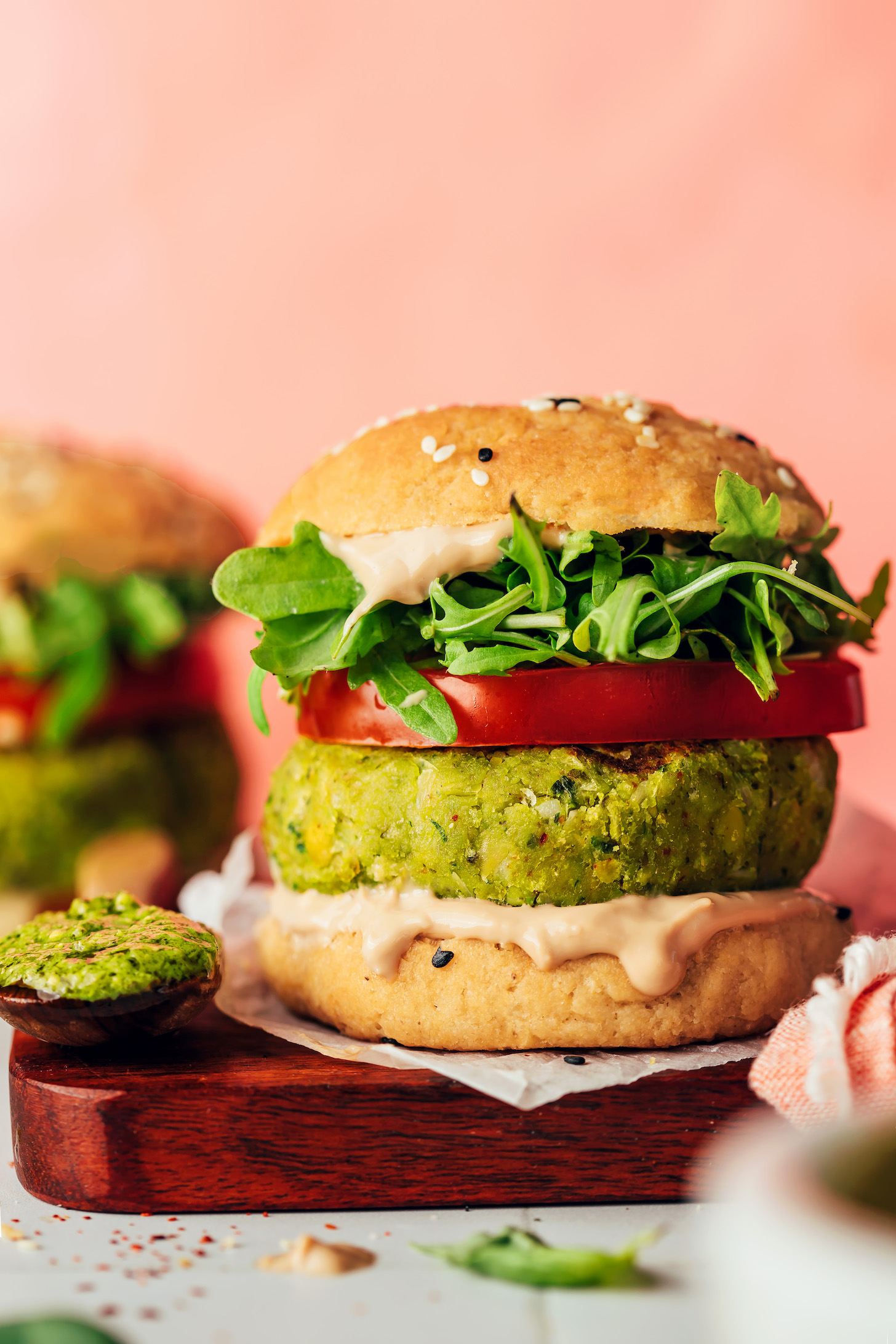 Side view of a pesto veggie burger on a bun with toppings