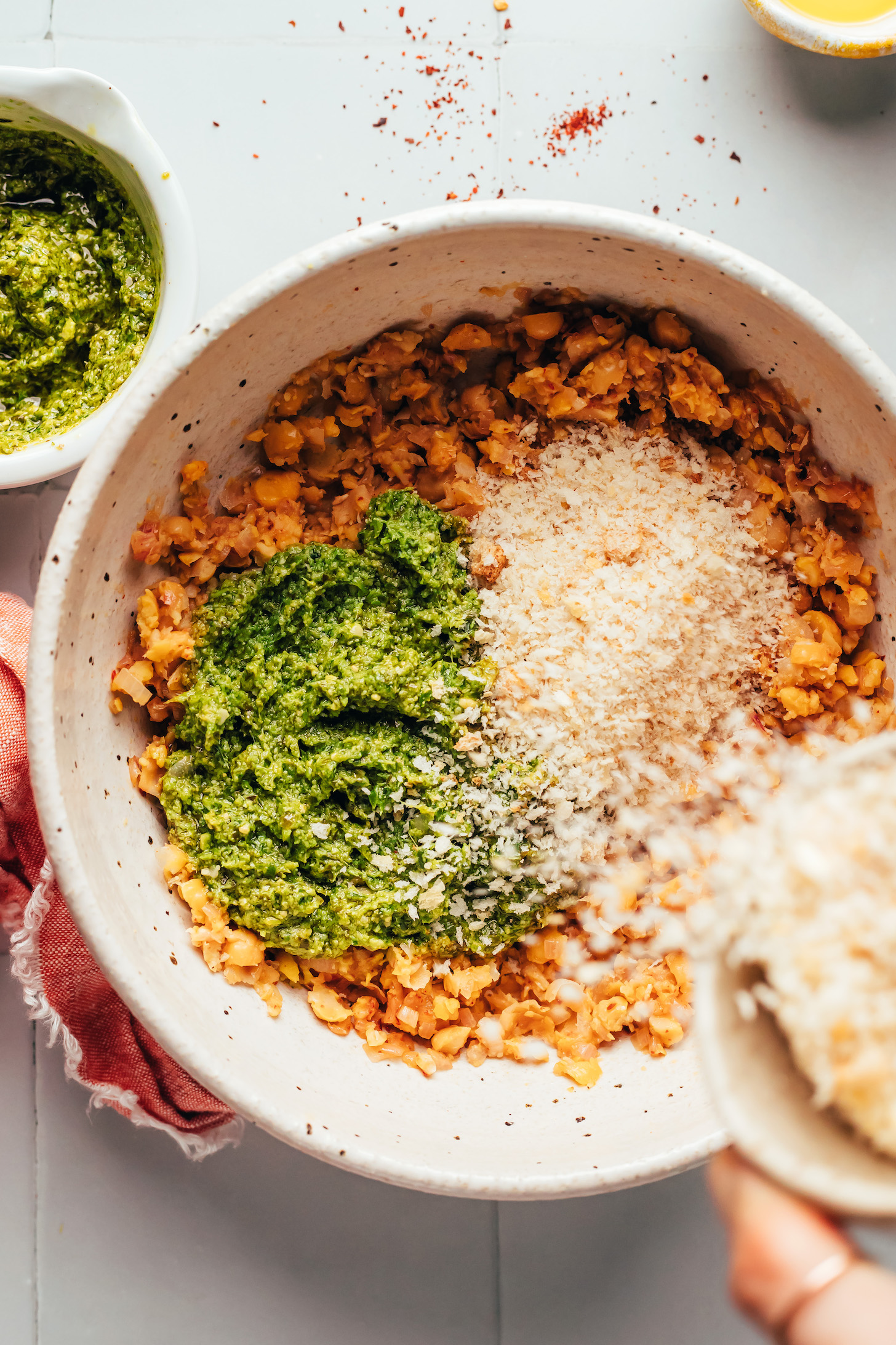 Adding breadcrumbs to a bowl with mashed chickpeas and pesto
