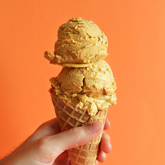 Holding up a waffle cone with two scoops of homemade Pumpkin Pie Ice Cream