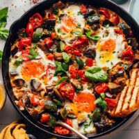 Slice of toasted bread in a pan of skillet ratatouille and eggs