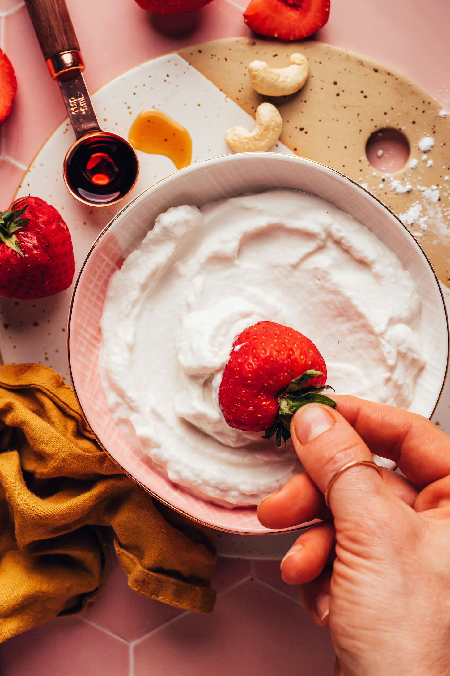 Dipping a fresh strawberry into a bowl of cashew whipped cream