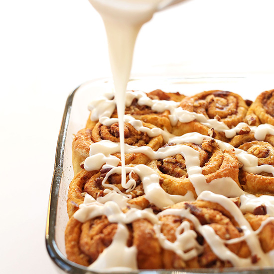 Drizzling icing onto a batch of delicious Vegan Pumpkin Cinnamon Rolls