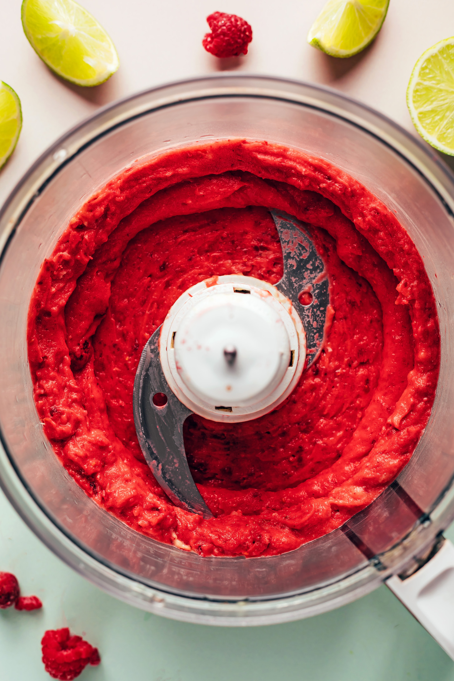Blended raspberry, pineapple, and mango mixture in a food processor